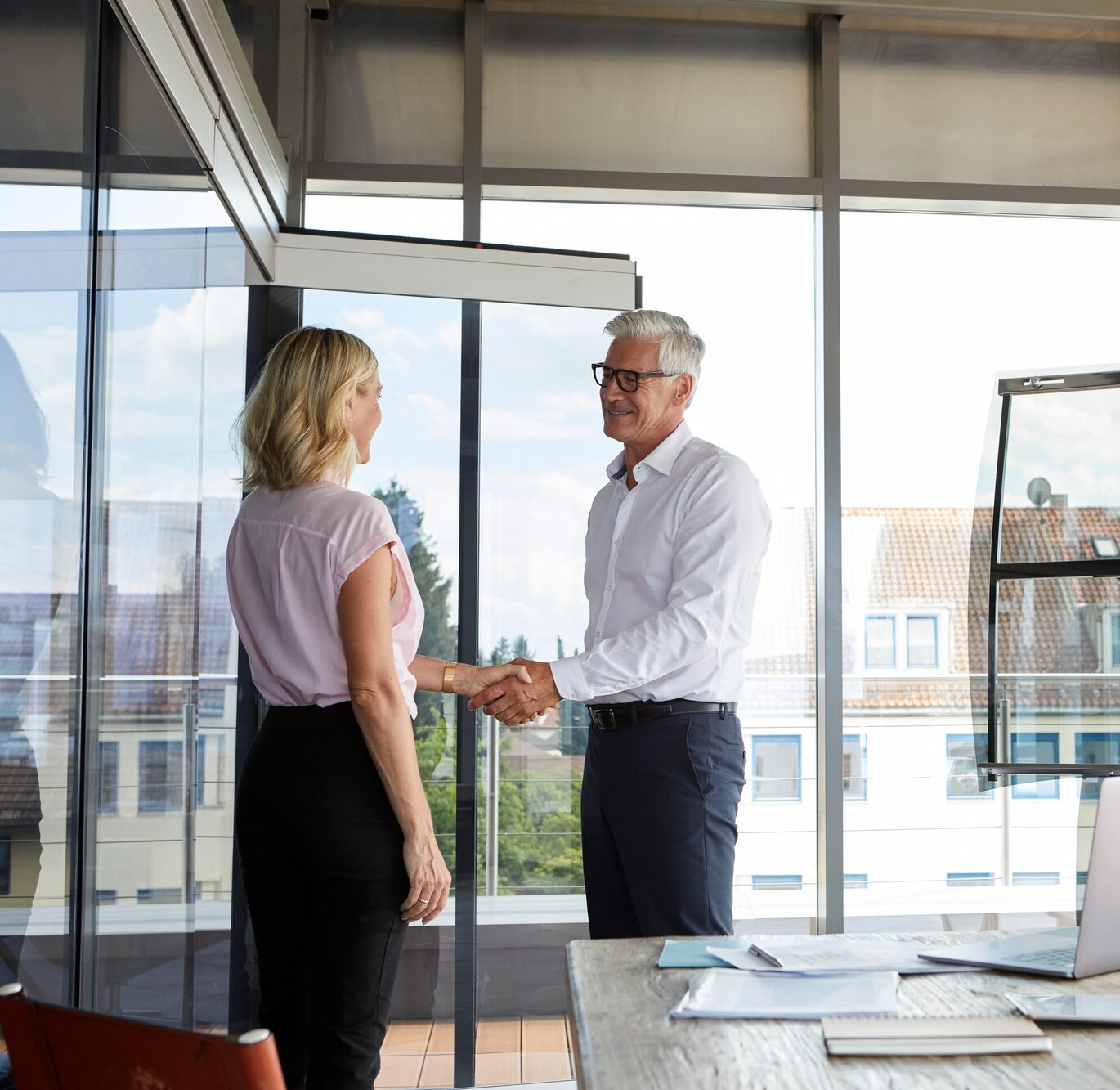 Businessman and woman shaking hands in office